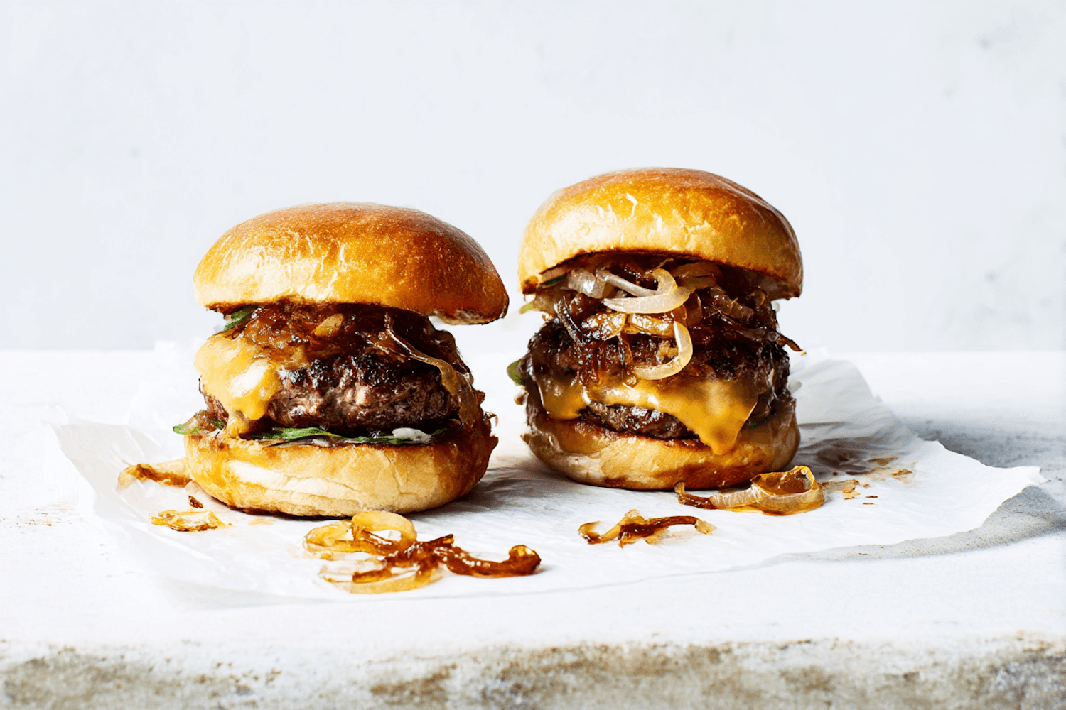 Two smash burgers with melted cheese and caramelised onions on brioche buns