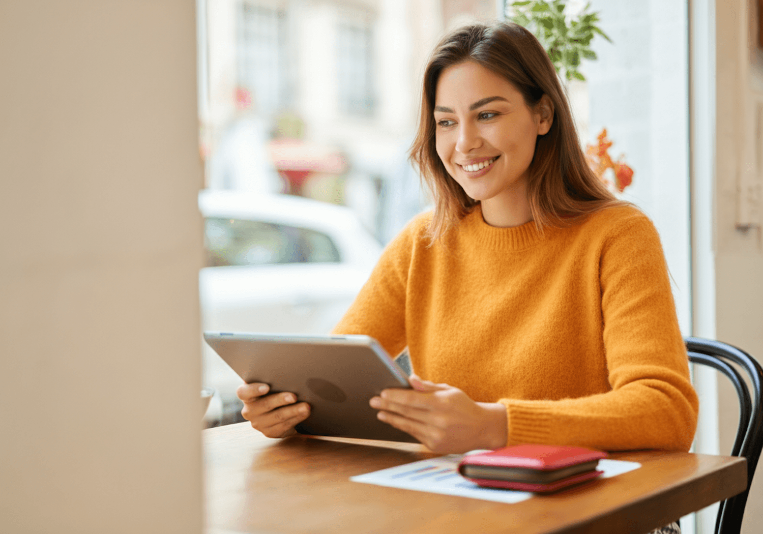 Smiling woman browsing a tablet at a café table